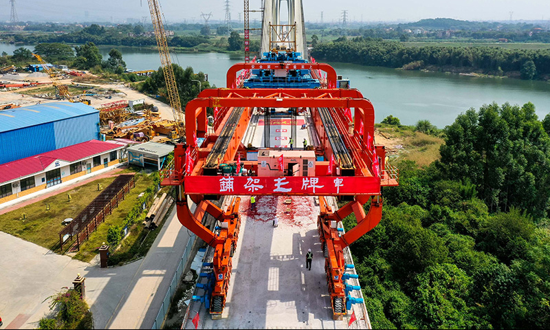 10月25日，施工人員操作架橋機將最后一孔900噸箱梁成功架設在增江特大橋橋墩上（無人機照片）。新華社記者 劉大偉 攝