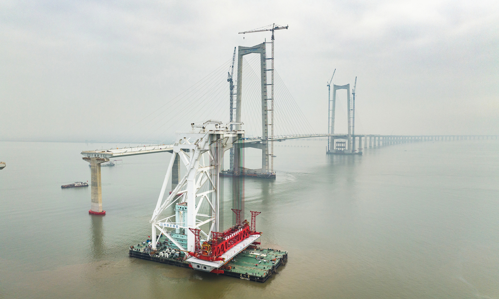 面對項目海域箱梁架設具有運輸線路長、穿越航道多、箱梁噸位重，架設精度要求高等難點，中鐵大橋局采用國內首創單體船型結構、全電力推進的海上架梁施工專用起重船“天一號”開展架設施工。圖為11月10日拍攝的深中通道施工現場。