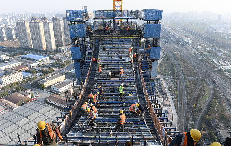 由中鐵十一局承建的跨襄陽北編組站大橋的全長920米，為雙獨塔雙索面混合梁斜拉橋；其中跨越鐵路站場部分總長度為520m，跨越鐵路32個股道，為國內跨越鐵路股道最多的橋梁。T3主塔塔高117米。圖為12月14日，工人在跨襄陽北編組站大橋T3主塔上施工。新華社記者 程敏 攝