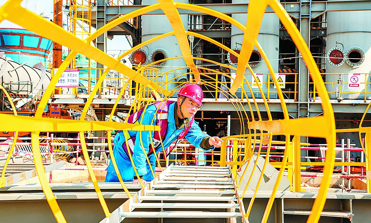 近日，中國石化揚子石化高質量推進煉油結構調整項目建設，大力推廣模塊化施工，主體設備吊裝前“穿衣戴帽”，對設備平臺等實行地面安裝焊接，有效降低高空作業安全風險。圖為施工人員檢查塔梯焊接質量。