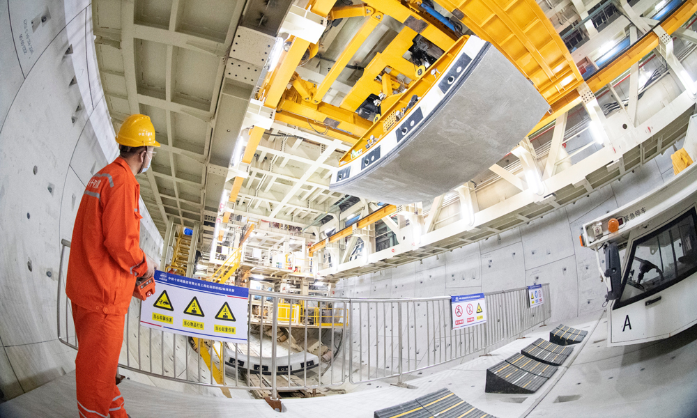 據介紹，上海機場聯絡線在國內首次采用全預制裝配結構體系，開創了類似施工工藝先河。面對預制構件體量大、單構件尺寸大、安裝節點精度要求高、拼裝難度大等要求，項目團隊成立工匠工作室，圍繞全預制拼裝開展課題研究，在國內首次研發弧形件精調裝置，將拼裝精度控制在1毫米以內；在國內首次研發應用中隔墻拼裝設備，實現中隔墻的自動抓取到精度控制的智能一鍵式拼裝，單月最高拼裝達到1200米，創造了全線最快拼裝記錄。圖為施工人員正在進行隧道管片吊裝。