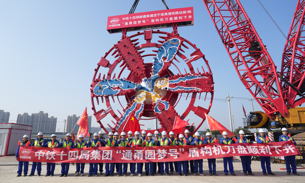 通甬高速鐵路是國家“八縱八橫”高速鐵路網沿海大通道的重要組成部分，自鹽城至南通高鐵南通西站起，向南經江蘇省蘇州市，浙江省嘉興市、寧波市，引入寧波樞紐寧波站，線路長301公里，設計時速350公里。建成后，將大幅拉近長三角核心區主要城市間的時空距離，對于優化長三角高鐵路網布局乃至完善全國交通網絡、推進長三角更高質量一體化發展、實現區域資源優勢互補和全面協調發展都具有重要意義。圖為建設團隊與刀盤合影。