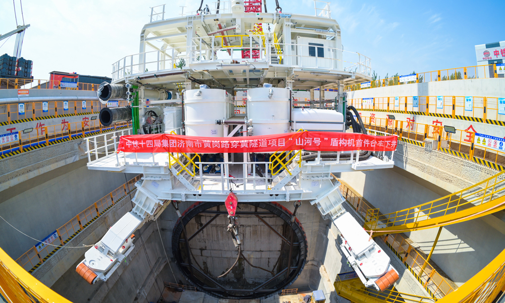 針對項目地質情況量身定制的“山河號”，最大開挖直徑17.5米，盾構機總長163米、重達5200噸、裝機總功率12580千瓦，盾構機總裝達到世界先進水平。本次吊裝下井的一號臺車，是“山河號”盾構機后配套臺車中最大、最關鍵的一節，重510噸，長約30米；設計為三層框架結構，搭載盾構機掘進的主要設備。考慮其龐大的尺寸和重量，分三段采用后、中、前的順序，由800噸履帶吊從始發井端頭依次吊裝下井，在井下指定位置完成組裝工作。圖為盾構機臺車下井。