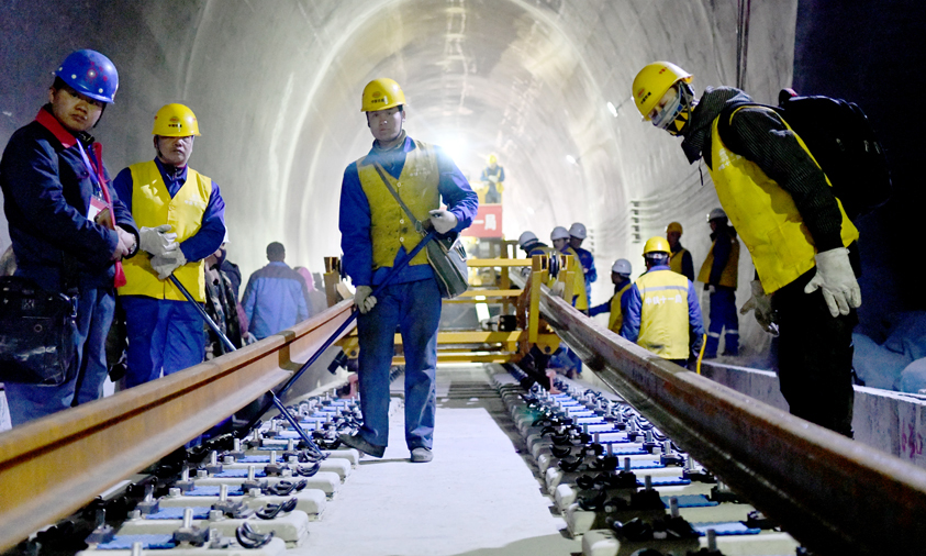 據介紹，拉林鐵路路基、橋梁為有砟軌道，鋪軌采取先鋪短軌排再換長鋼軌的換鋪法，香嘎山隧道是拉林鐵路首次采用長鋼軌鋪設的隧道。圖為工作人員在香嘎山隧道鋪設長鋼軌。