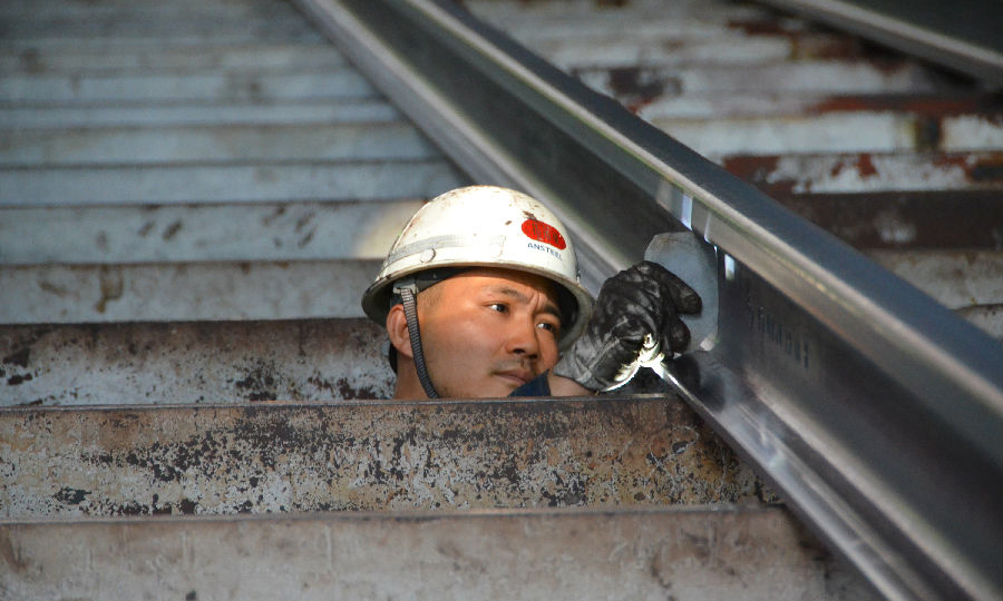 圖為工作人員正在大冷床上卡量剛剛軋制出來的百米長定尺75kg/m重軌。