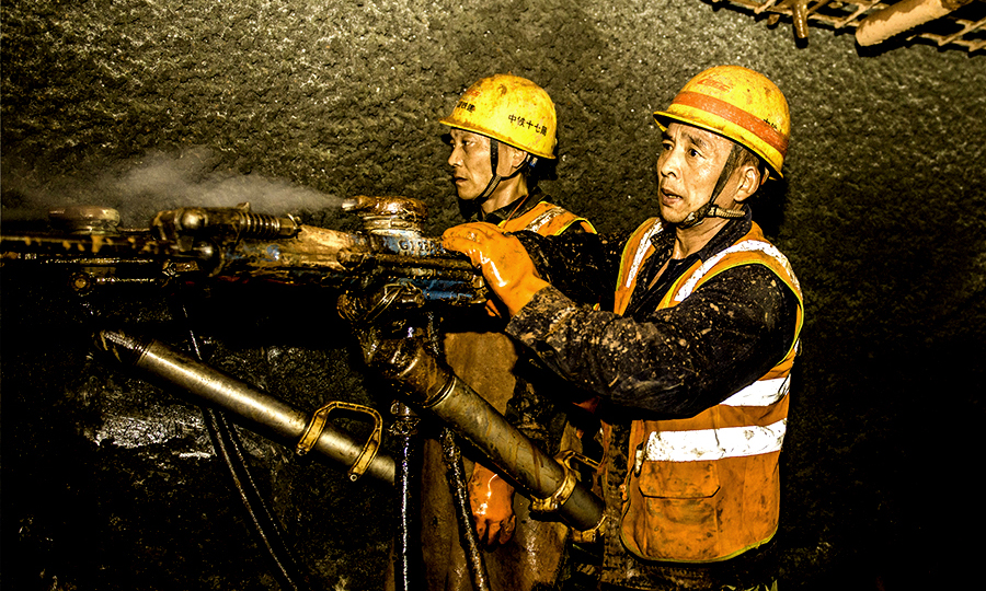 布喀木隧道位于西藏自治區米林縣境內，全長9240米，最大埋深約為1381米，最高地溫約為42攝氏度，巖爆區占90%以上，面臨風積沙、突水等不良地質難題。項目部在全線率先采用水壓光面爆破和聚能水壓光面爆破技術，發明應用智能噴霧降塵裝置等新裝備，破解一個個不良地質難題，確保工程安全優質高效推進。圖為拉林鐵路布喀木隧道施工現場。