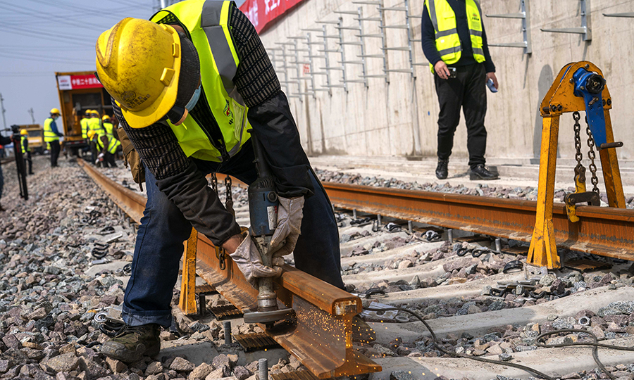 目前，該項目正在進行錦秋路站至顧村公園站區間上下行線無縫線路焊軌、陳太路停車場碎石道床施工。為兌現工期節點目標，項目部正在組織長風公園站基地、姚虹路基地施工人員陸續進場，盡快恢復全標段施工。圖為上海地鐵15號線鋪軌B標工人師傅正在進行除銹作業。
