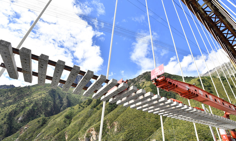 9月20日，伴隨著陣陣轟鳴聲，鋪軌機吊著一排25米長的軌排，緩緩落在藏木雅魯藏布江特大橋上，標志著拉薩至林芝鐵路第三座跨越雅魯藏布江特大橋已經鋪軌，至此正線鋪軌168公里，距離2021年建成通車更近了一步。圖為中鐵十一局工程技術人員在藏木特大橋上鋪軌。（新華社記者 覺果 攝）