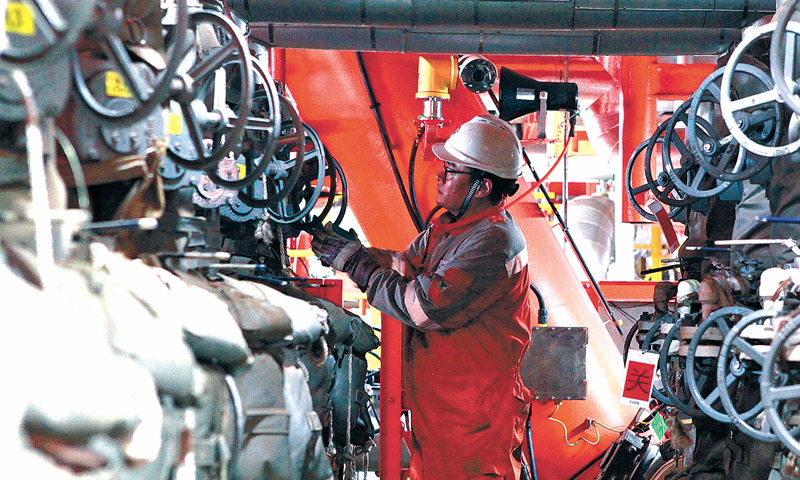 秦斌所在的中國海油旅大21-2油田包括通過冷采開發的A平臺和通過熱采開發的B平臺，自海上“安家落戶”后，兩個平臺便合二為一。整個平臺面積不大，分量卻不輕，B平臺作為我國首個規模化熱采技術集成示范平臺，肩負著單項熱采技術優化、系統熱采技術集成創新應用、熱采新技術試驗等示范性任務，對于渤海油田上產4000萬噸，保障國家能源安全都具有重要意義。圖為井口崗員工正在操作油井管匯閥門，準備對油井進行計量。