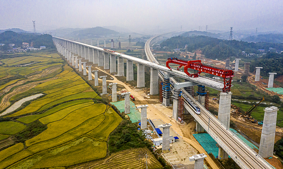 為保證施工順利進行，該項目部經過方案比選，采用了“門式墩鋼蓋梁+簡支箱梁”的形式跨越，大大降低了安全風險，有效縮短了施工周期，并降低了施工成本。圖為10月13日，一列動車從架梁施工現場通過。（彭特 攝）