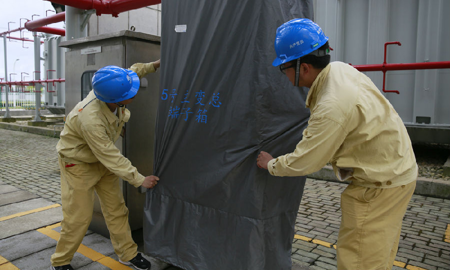 國華電力寧海電廠維護檢修部門充實防汛儲備物資的品種和數量,對經常性故障設備和室外設備進行精益化維護升級,確保設備在汛期穩定運行。圖為該廠團員青年對5號機主變區域控制室外電源箱加裝防雨布。