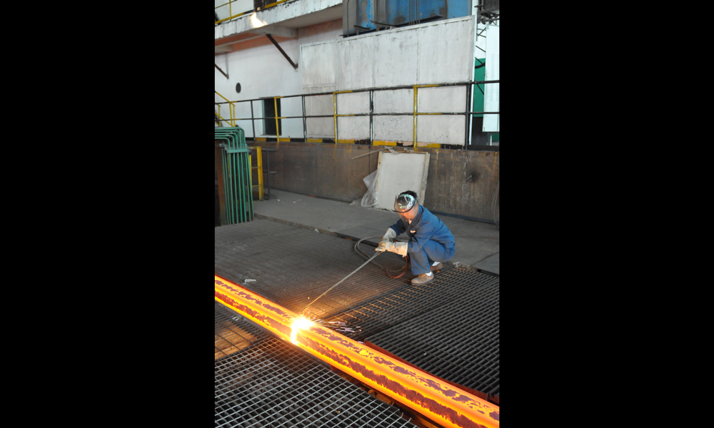 鋼坯冷卻區，青年拉矯工在手動切割鋼坯。（作者：韓先明）