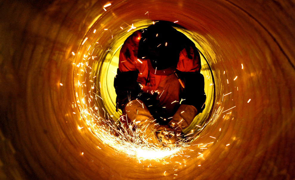 中國石油化工股份有限公司江漢油田分公司的一名工人在狹小的管道內工作。（作者：宋國梁）